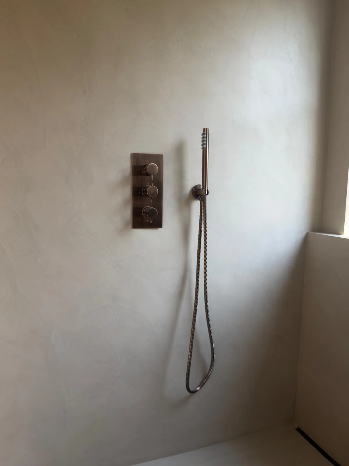 Fugenlose Mikrozement-Dusche mit eleganter Armatur und minimalistischer Wandgestaltung